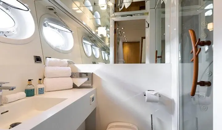View of a yacht cabin with beige seating, wood paneling, and a bathroom door
