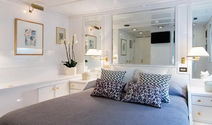Interior of yacht cabin with bed, decorative pillows, and wall-mounted TV