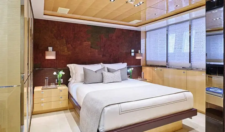Master cabin with king bed, white sheets, wooden headboard, bedside lamps