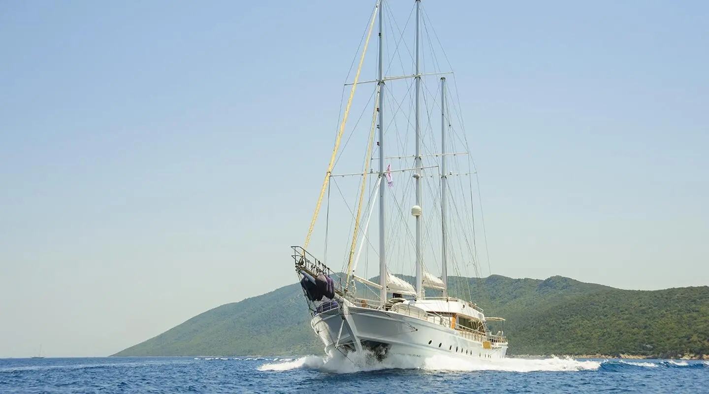 Yacht Bella Mare sailing near clear blue water with sails raised