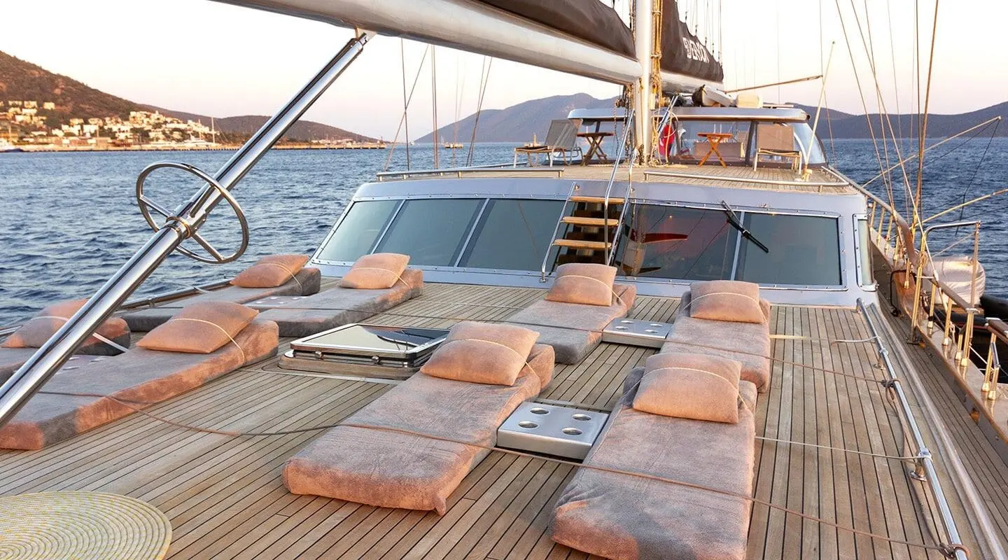 Sunlit deck seating on a gulet yacht with wooden loungers and ropes