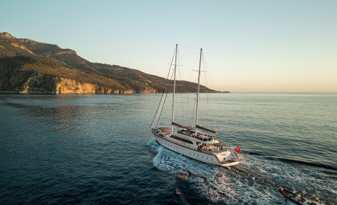 Luxurious sailing yacht with two masts sailing near calm sea and coastline