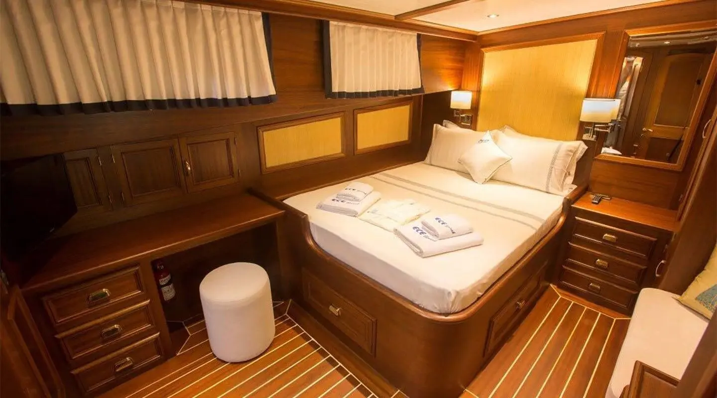 Interior of Ece Berrak yacht with a large bed, wood paneling, and warm lighting