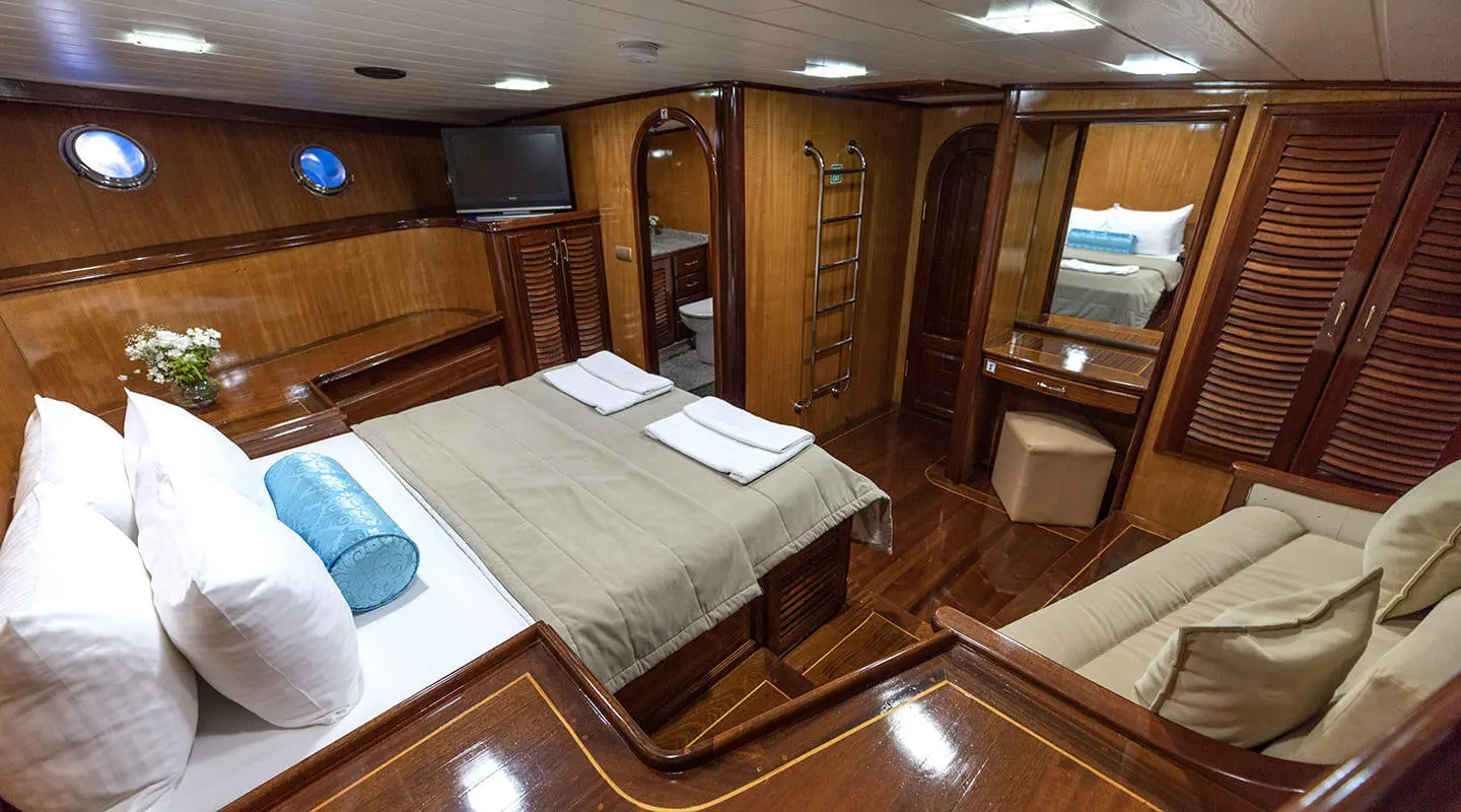 Luxurious wooden-styled cabin with a large bed, white pillows, and beige bedding.