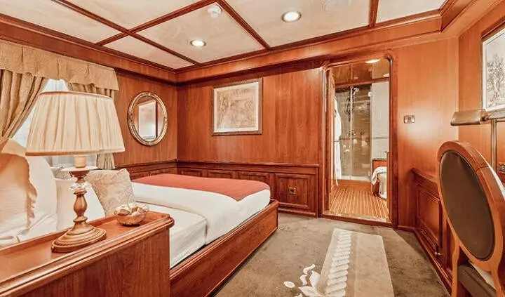 Seagull II yacht cabin with two beds, wooden panels, and porthole windows