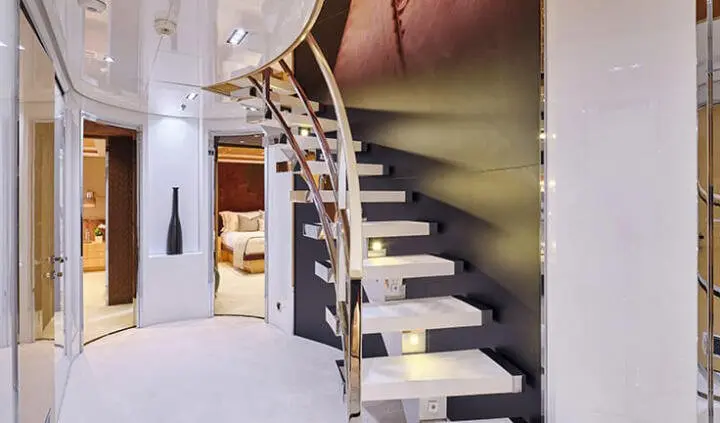 Staircase inside yacht with curved wooden steps and metal railing