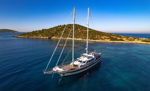 Double Eagle sailing yacht anchored near rocky coastline on clear blue Mediterranean water