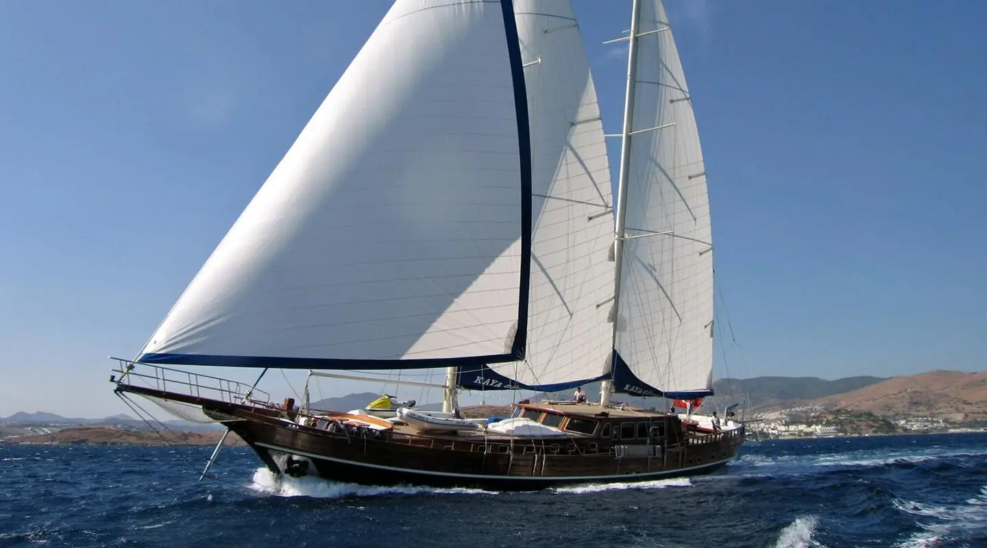 Yacht Kaya Guneri 4 sails at sunset with dark blue sea and clear sky