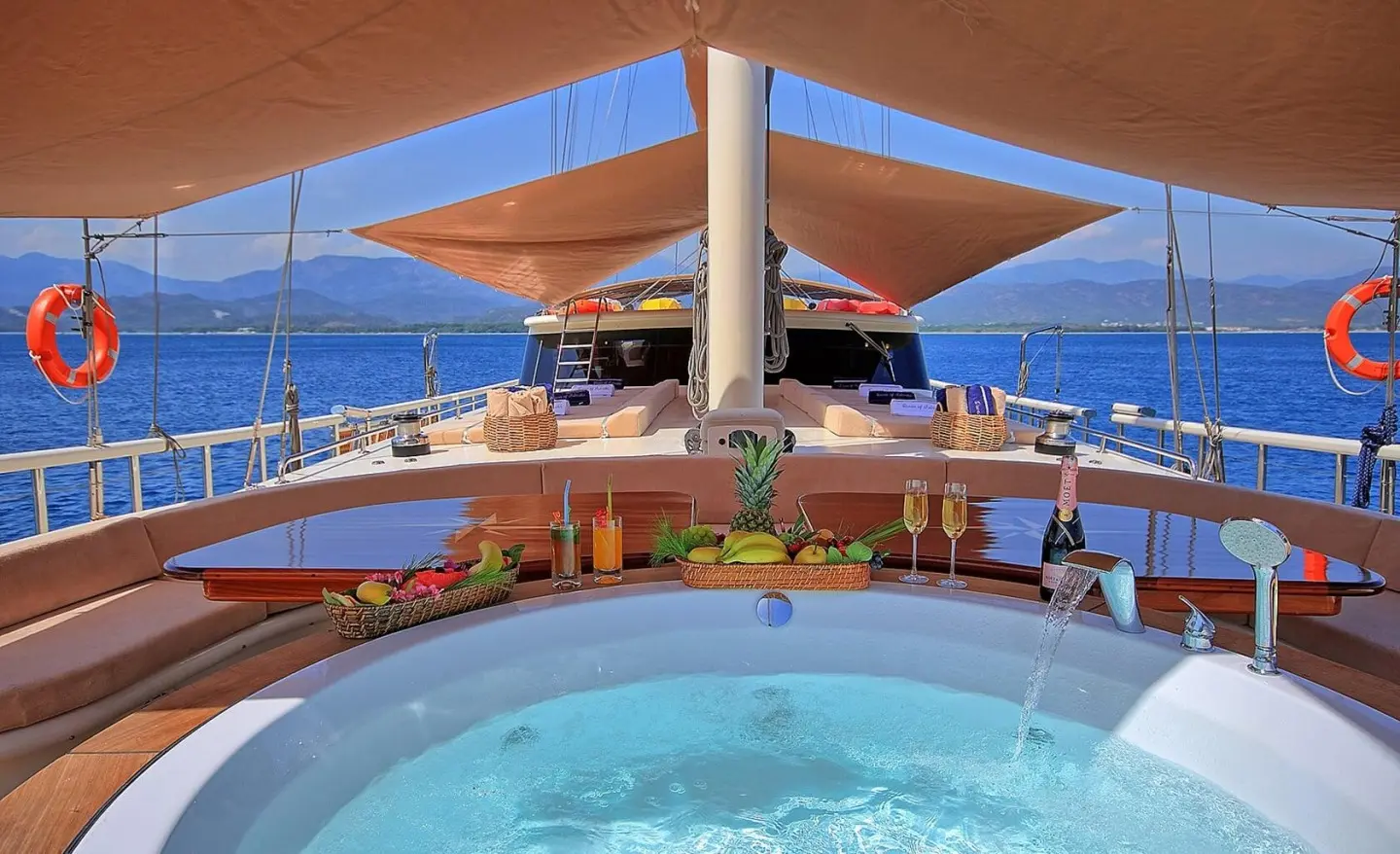 Queen Of Salmakis yacht deck with sun loungers under blue sails, pool in foreground