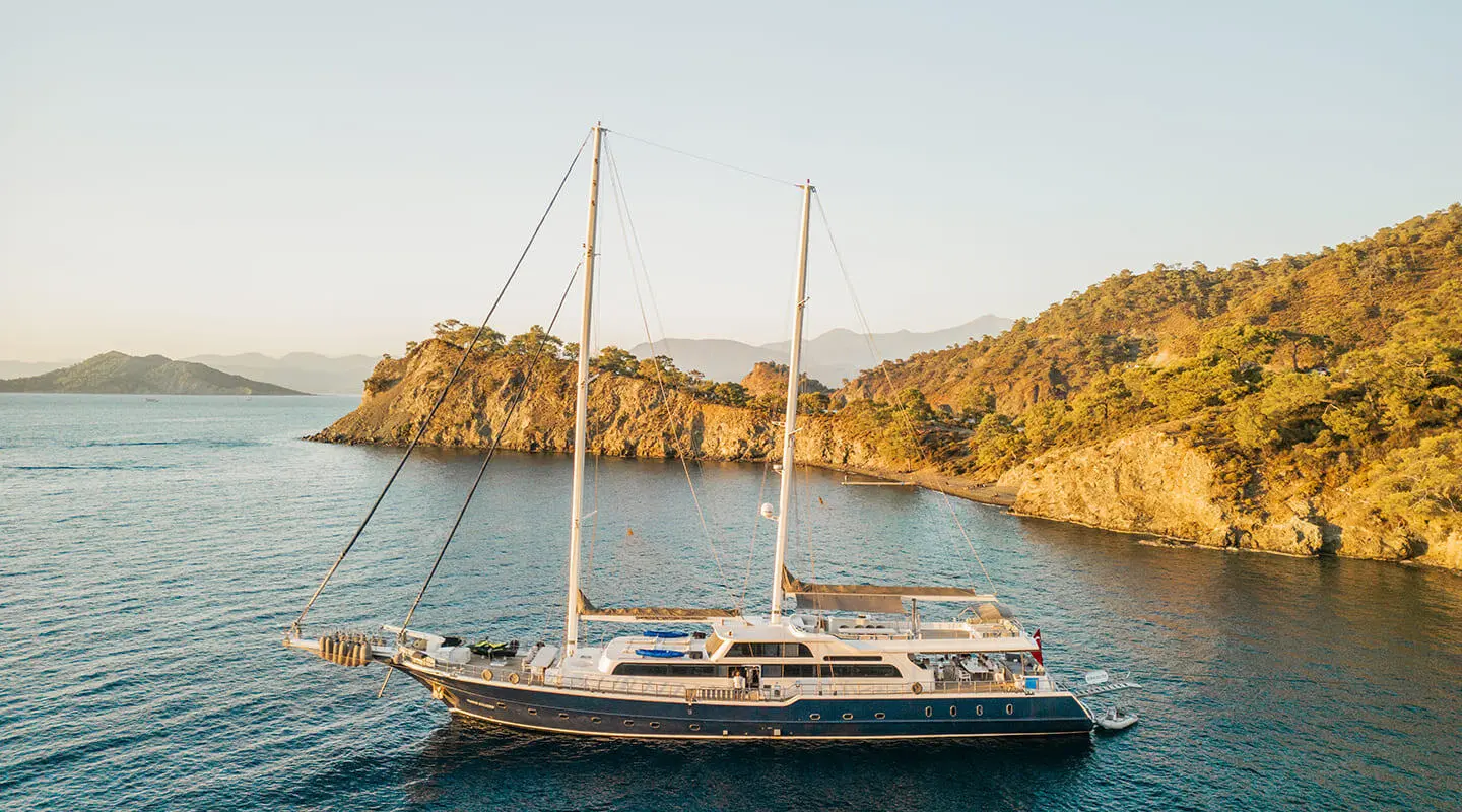 Esma Sultan luxury sailing yacht anchored near rocky coastline
