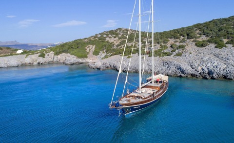 Zephyria II anchored in turquoise waters near rocky coastline and clear blue sky