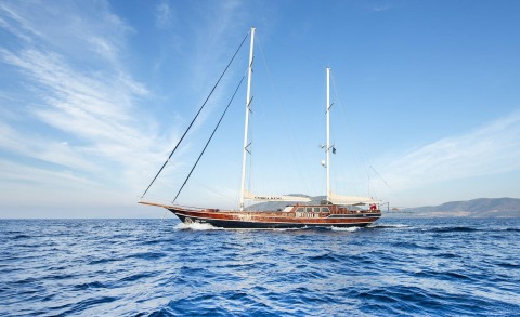 Wooden-hulled sailing yacht with two tall masts on the open sea