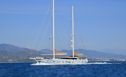 Queen Of Salmakis luxury yacht sailing on blue sea with two tall masts and beige bimini tops