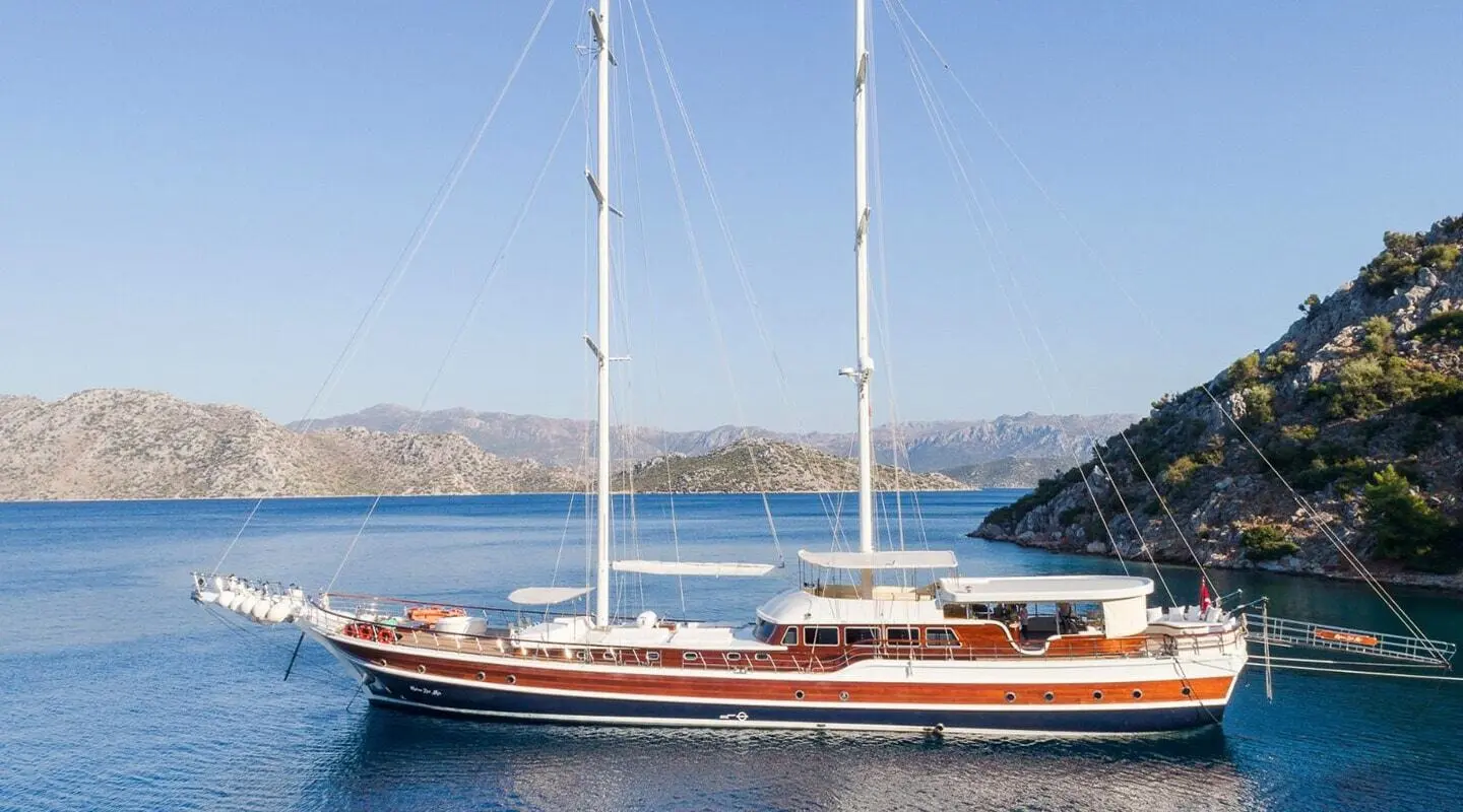 Halcon Del Mar sailing yacht anchored in blue Mediterranean waters near rugged coastline
