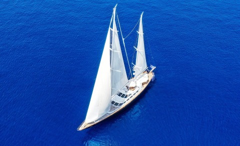 Overhead view of a white sailing yacht with two masts on blue sea
