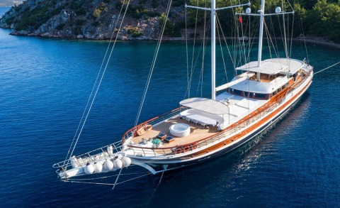 Halcon Del Mar luxury sailing yacht anchored off a rocky coastline with deep blue waters