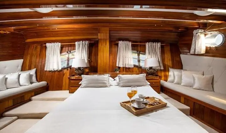 Master cabin with king bed, wood paneling, and bedside lamps on each side
