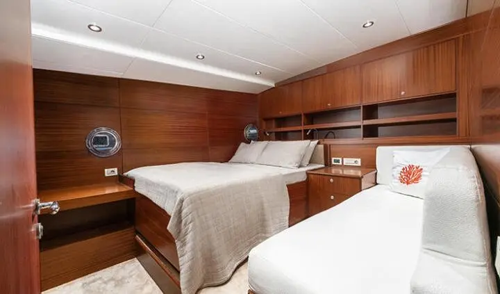 Twin cabin aboard Lucky You with wood paneling, two beds and built-in storage