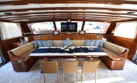 Luxurious wood-paneled interior with a long seating area, table, and TV in front of striped cushions