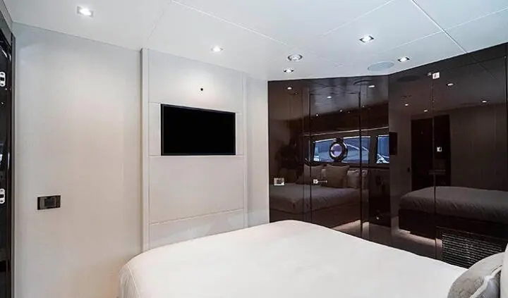 Queen bed in cabin with mounted flat screen TV and white walls