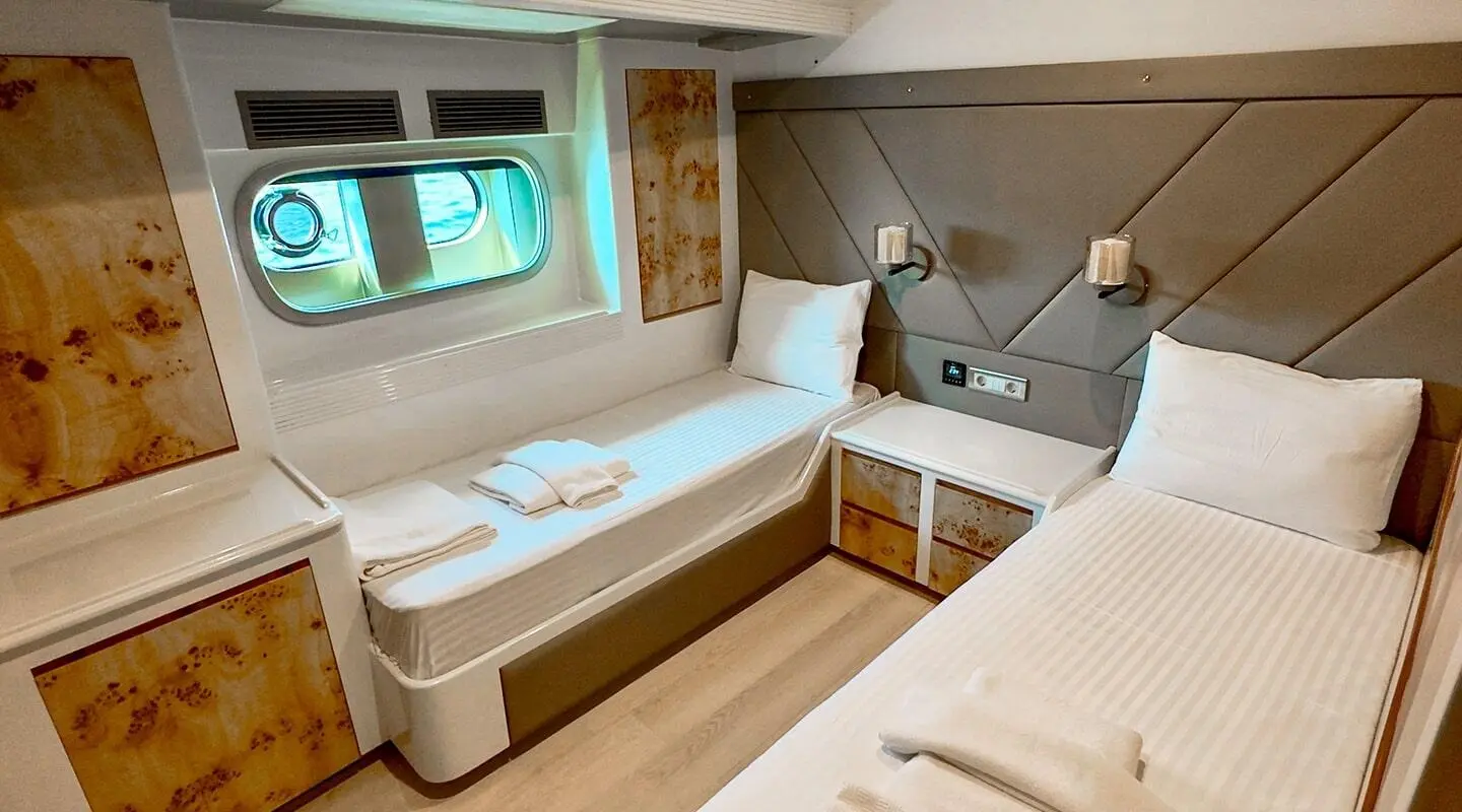 Angelo III yacht interior with airy cabin, white cushions, porthole view, and wood accents