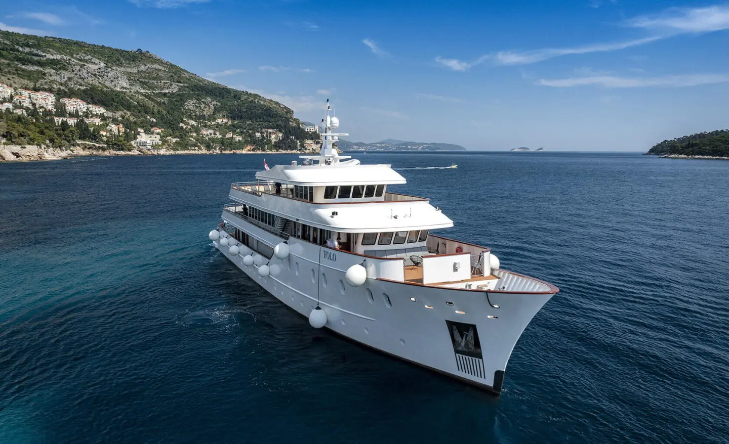 Yolo luxury yacht sailing on blue sea near coastline at sunset, multiple decks