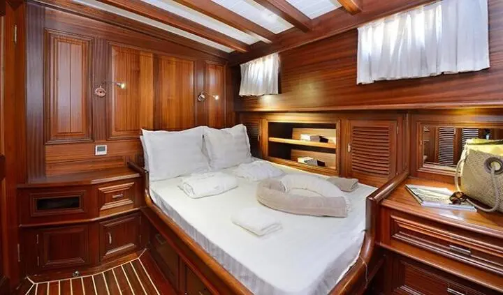 Cozy wooden cabin interior with a double bed and white linens on a yacht