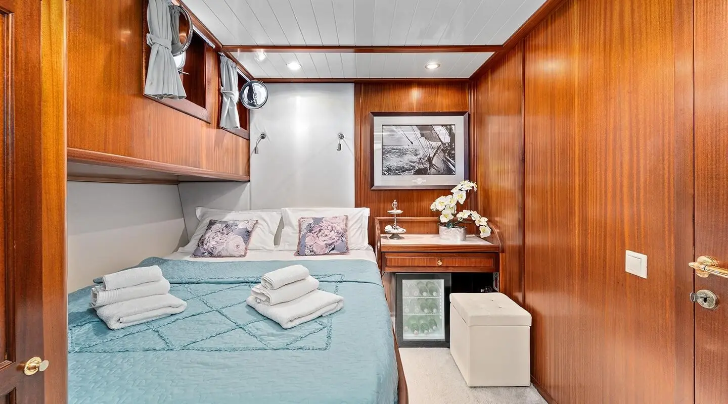 Interior of Smart Spirit yacht cabin with bed, wood cabinets, and a small seating area