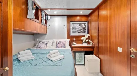 Interior of Smart Spirit yacht cabin with bed, wood cabinets, and a small seating area