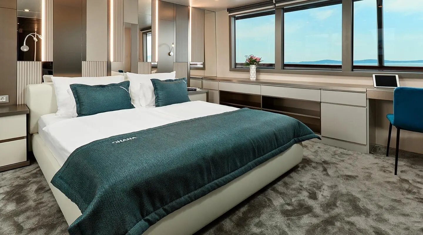 Ohana 49m yacht bed deck: neatly made bed, pillows, and windowed cabin