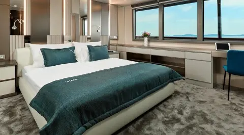 Ohana 49m yacht bed deck: neatly made bed, pillows, and windowed cabin