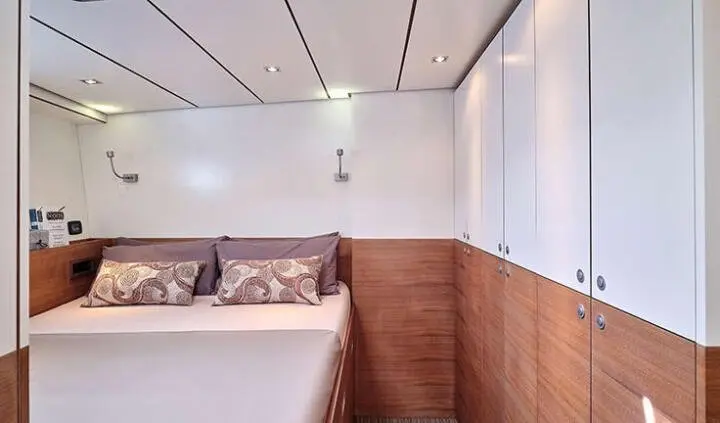 Aizu yacht master cabin with king bed, white bedding, wooden paneling, windows on right