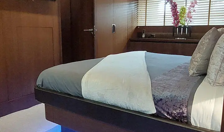 Master cabin with king bed, white linens, dark wood panels, and bedside lamps