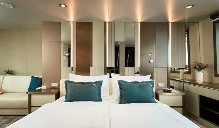 Ohana yacht cabin with a king bed, two turquoise accent pillows, and ensuite doorway