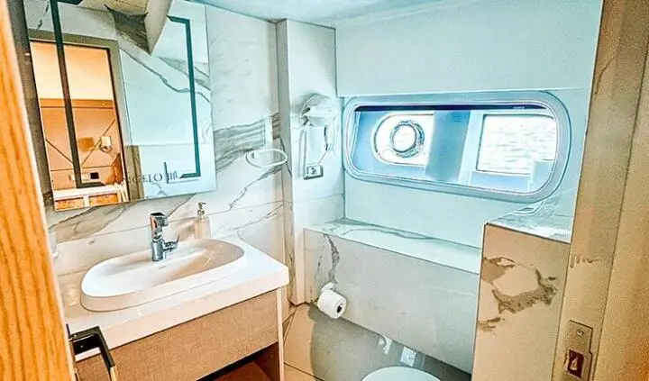 Angelo III cabin interior with bed, porthole window, and compact bathroom scene