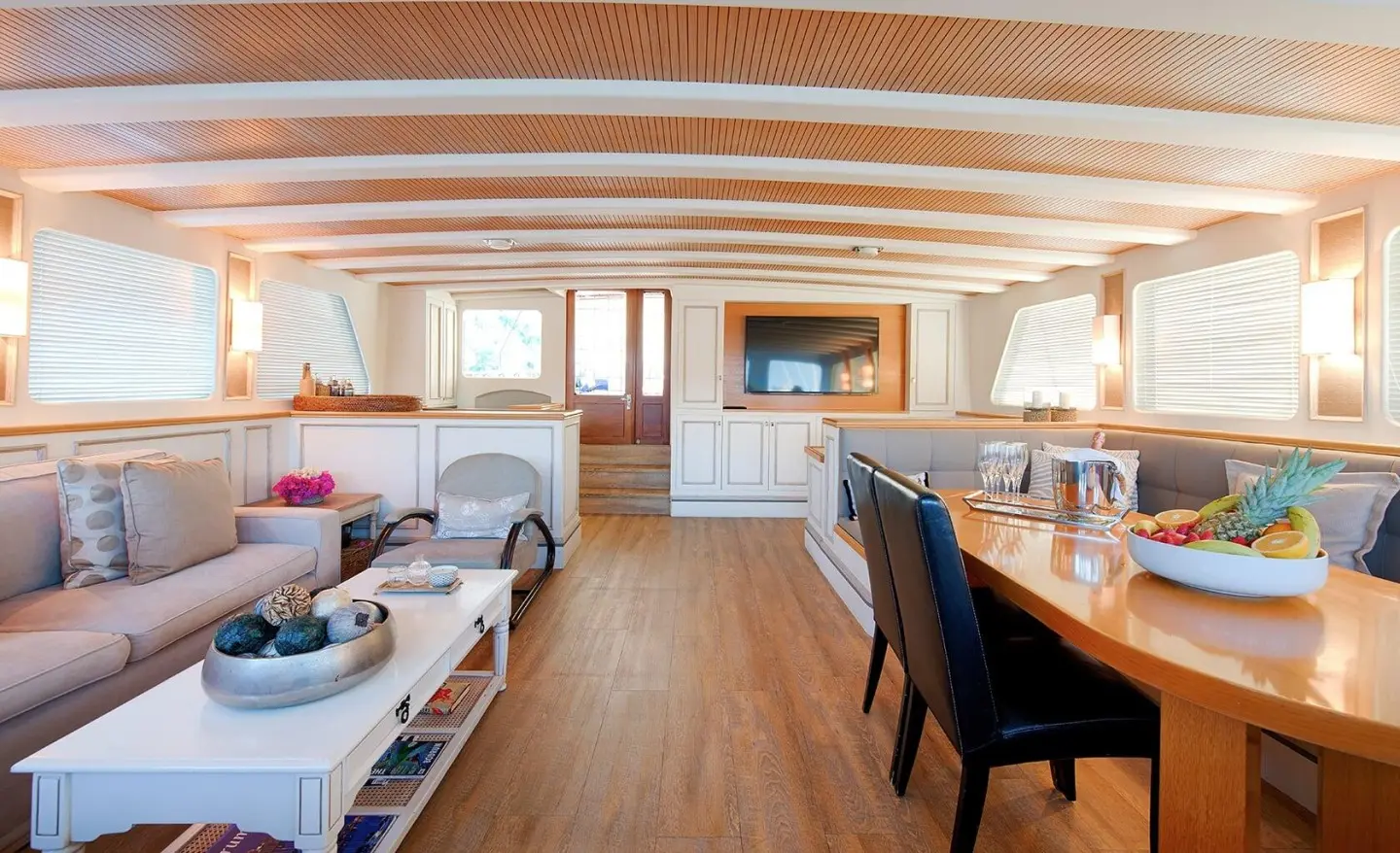 Interior of Cobra King yacht with seating, table, and warm wooden panels at sunset