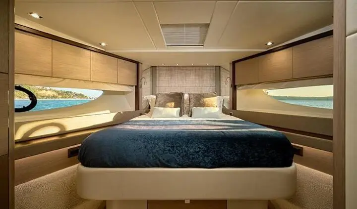 Master cabin with king bed, blue bedspread, wood cabinetry, windows, lighting