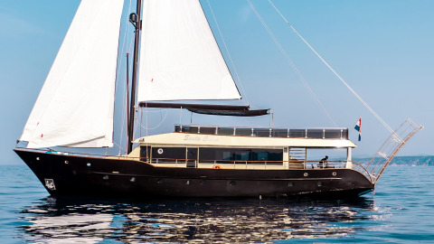 Luxurious black and white sailing yacht on calm sea with deck railing