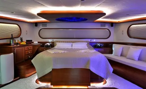 Dolce Mare yacht interior with a bed, seating, and warm lighting at sunset