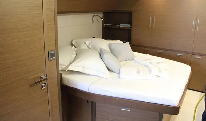Atlantis yacht cabin interior with plush bed, white linens, and built-in wooden cabinetry