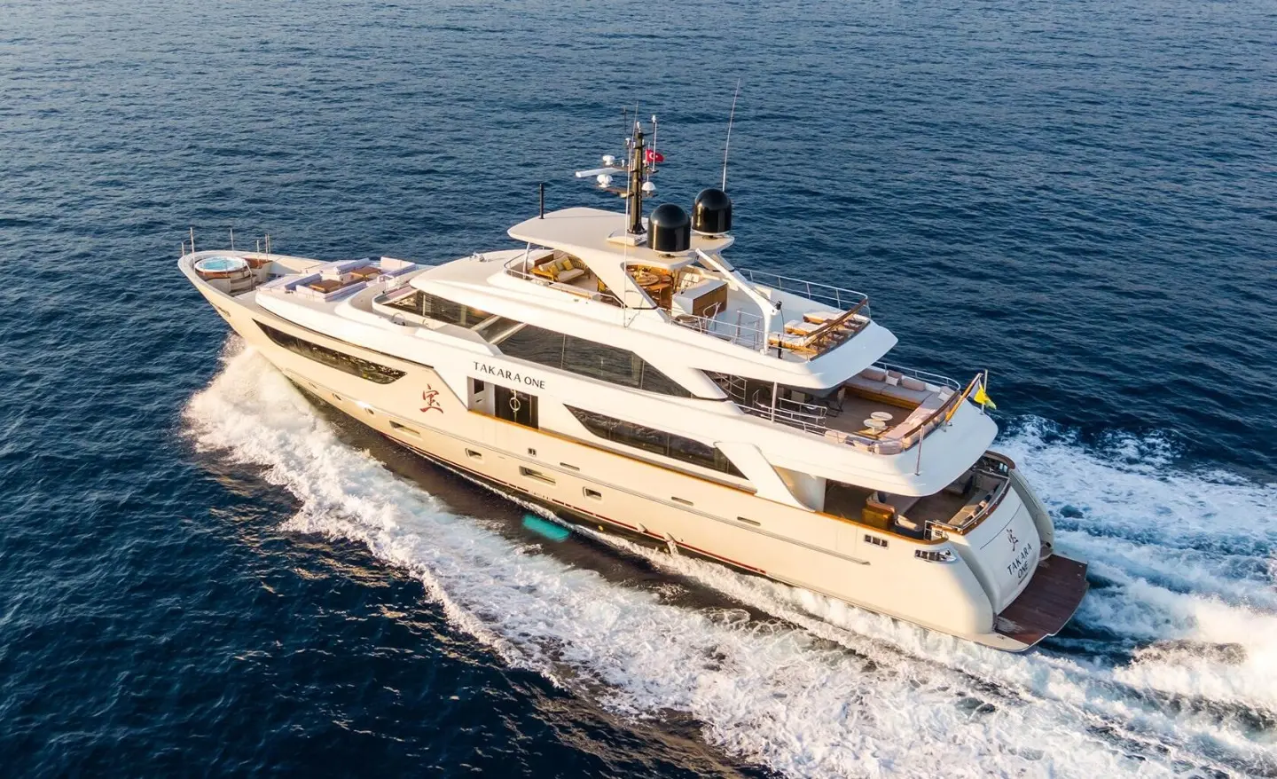 Yacht Takara One cruising on blue sea, white hulls slicing waves, from above