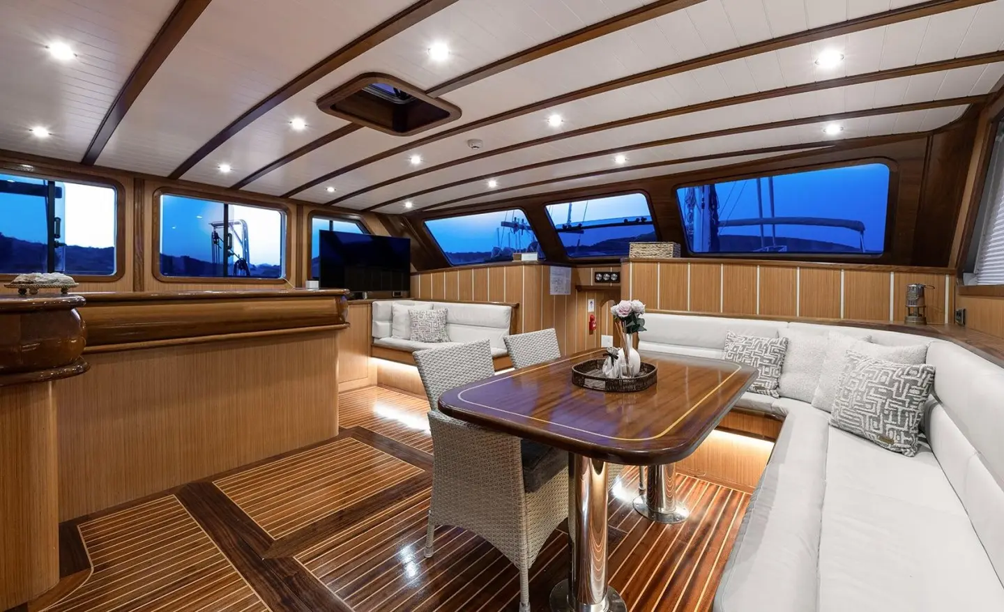 Wooden deck interior with white seating and table, side windows