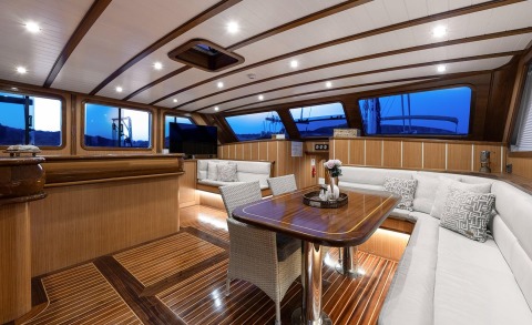 Wooden deck interior with white seating and table, side windows