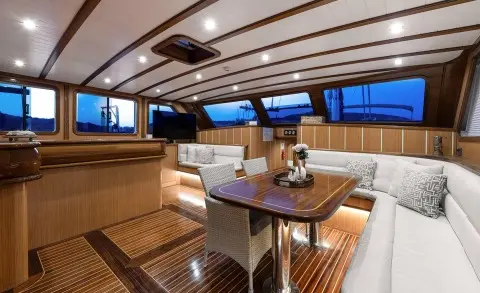 Wooden deck interior with white seating and table, side windows