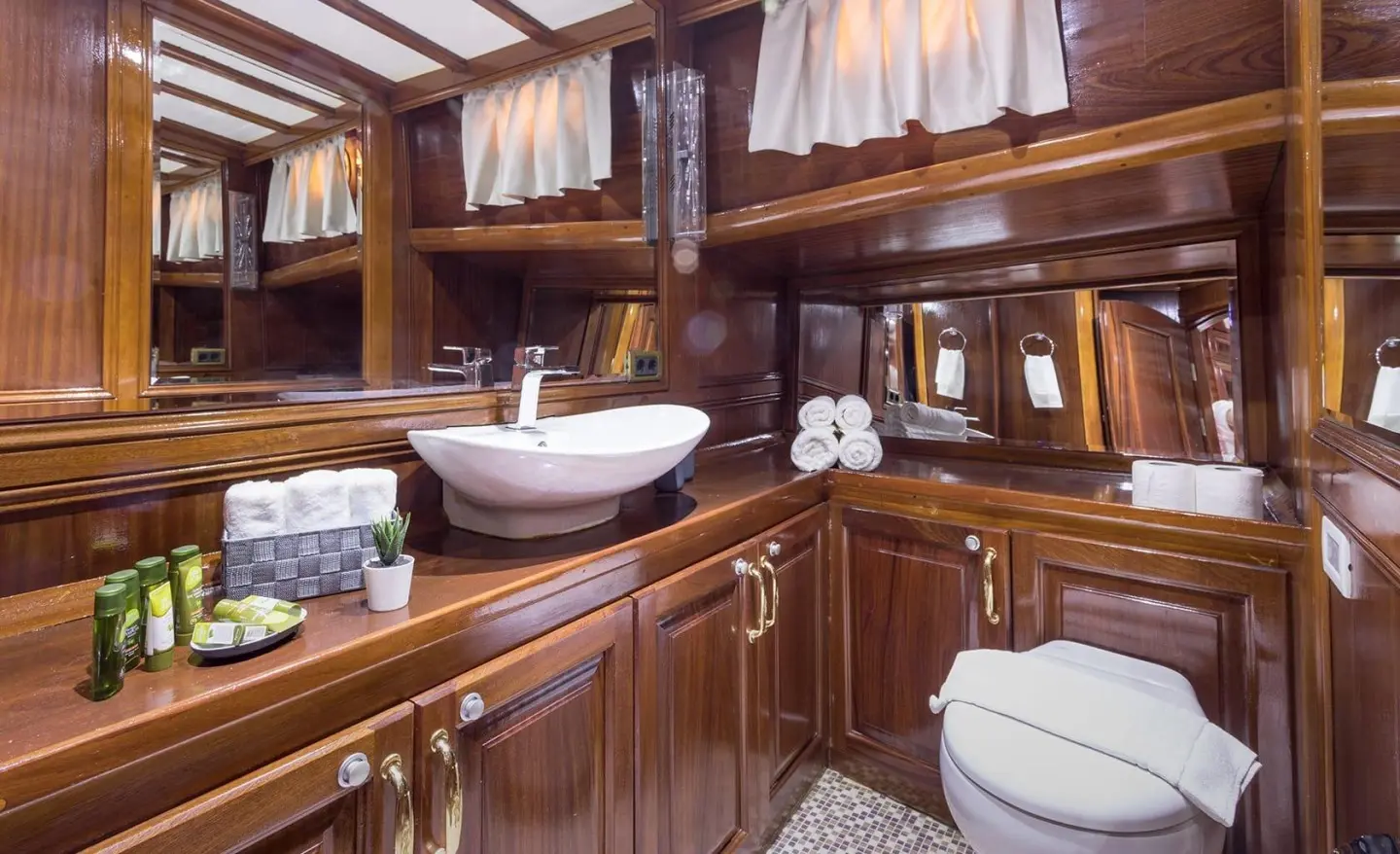 Grace 1 yacht interior with polished wooden cabinetry, brass fixtures, and cushioned seating.