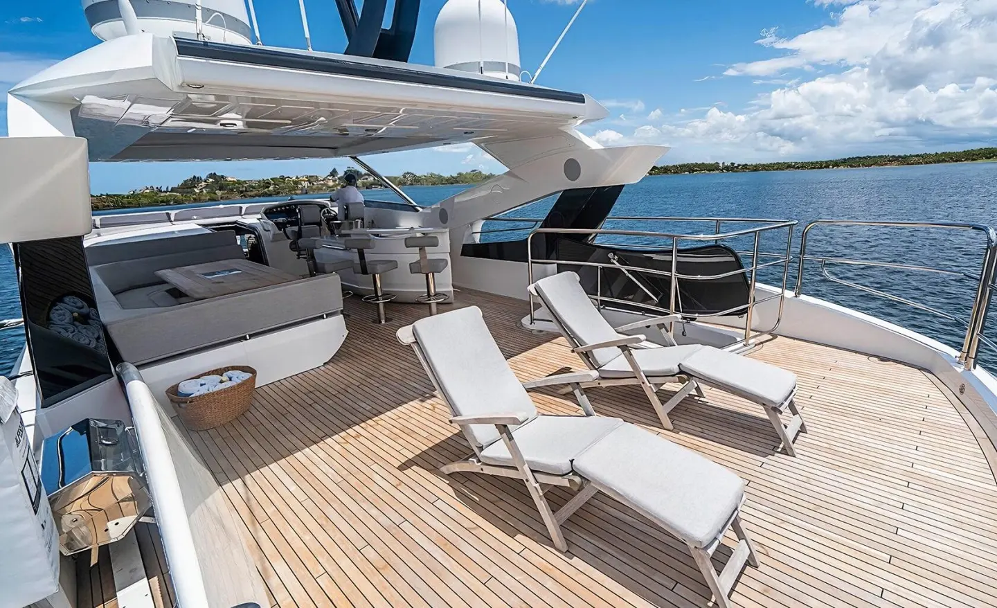 A luxury yacht Quantum deck with sun loungers under a shaded area, calm sea