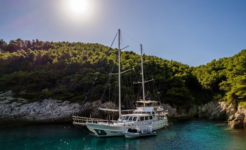 Maske yacht, a 27.5 m gulet, anchored in a cove with its deck and masts visible