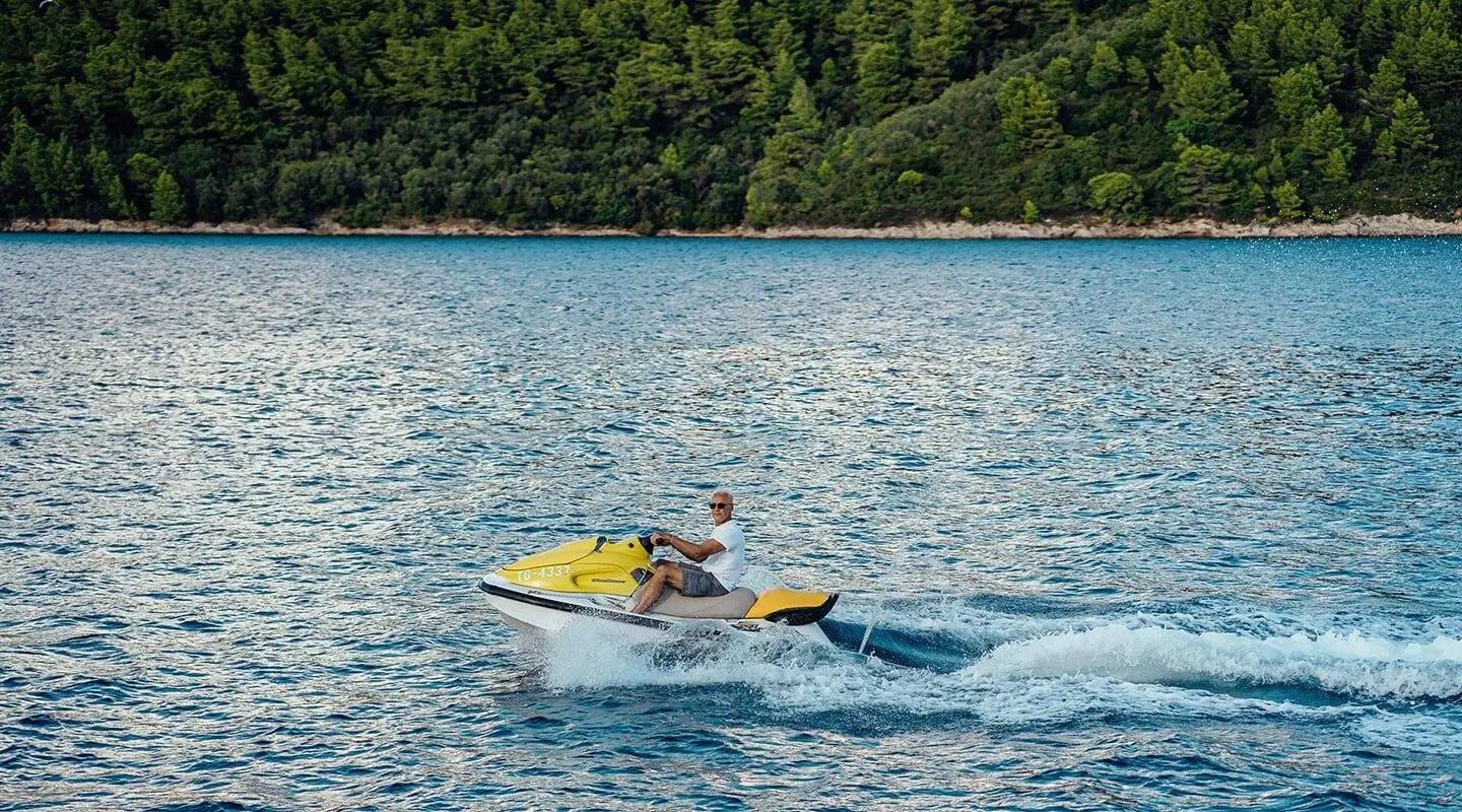 Maske yacht sailing at sunset with two people on a small motorboat nearby