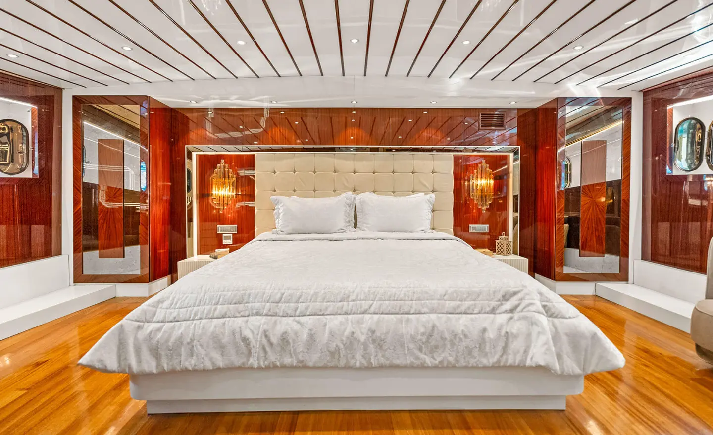 Luxurious yacht cabin with large bed, white bedding and wood floor