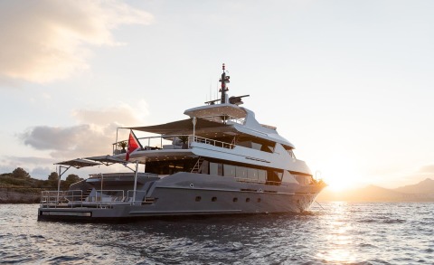 Large white yacht Illusion II anchored on sunset, with multiple decks and open deck areas visible